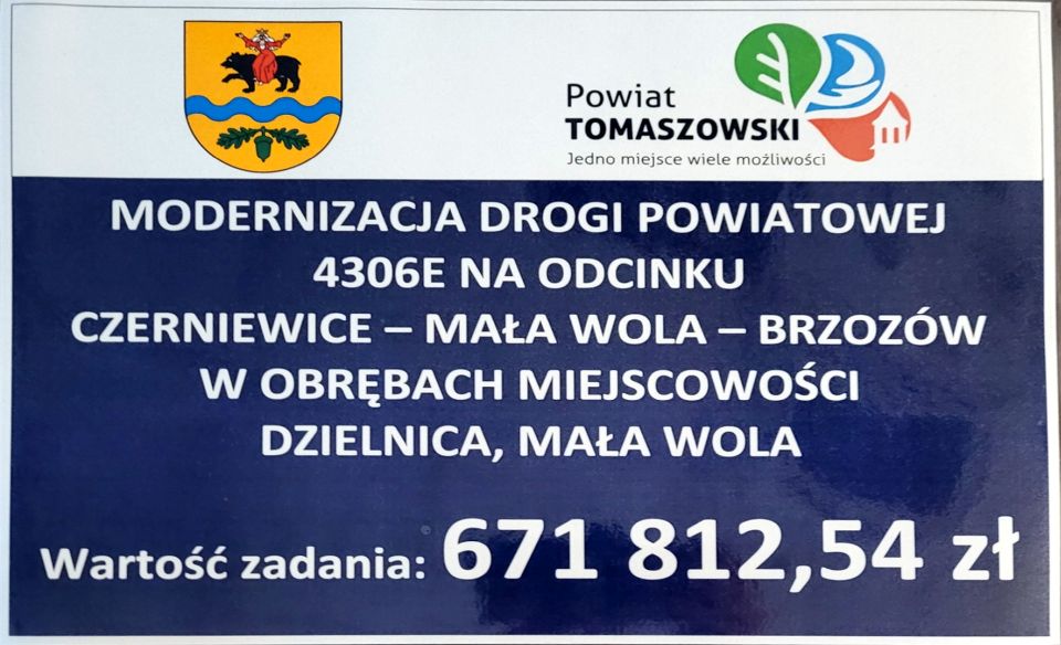 Na zdjęciu: baner dotyczący inwestycji drogowej, realizowanej przez powiat tomaszowski. Na banerze napis: Modernizacja drogi powiatowej 4306E na odcinku Czerniewice – Mała Wola - Brzozów w obrębach miejscowości Dzielnica, Mała Wola. Wartość zadania: 671 812,54 zł