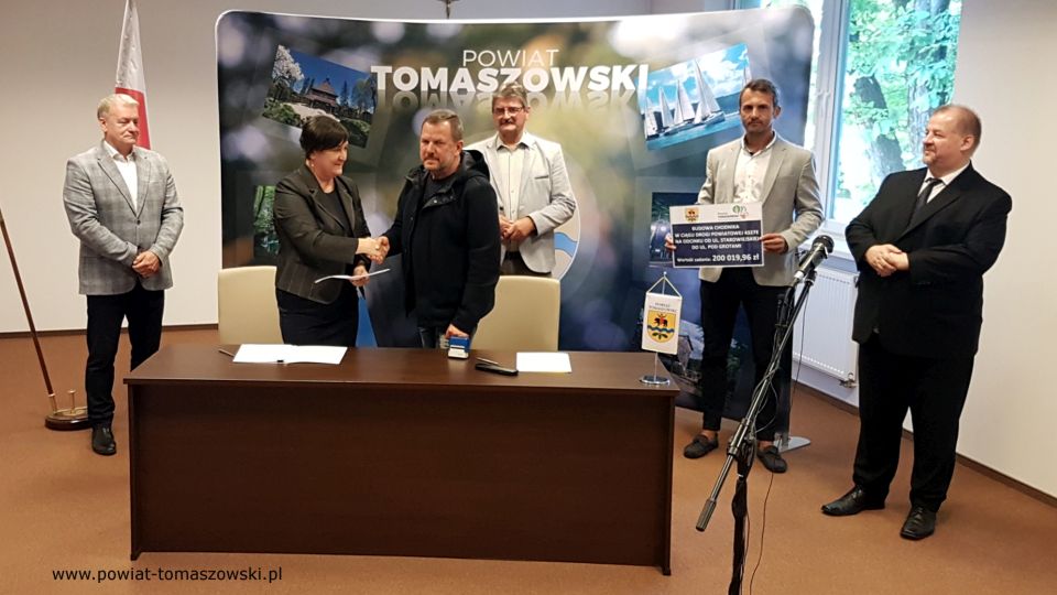 Na zdjęciu: od prawej: Mariusz Węgrzynowski – Starosta Powiatu Tomaszowskiego, Marek Kubiak – członek Zarządu Powiatu Tomaszowskiego, Leszek Ogórek – Wicestarosta Powiatu Tomaszowskiego, Grzegorz Więckowski – współwłaściciel Firmy „Dromed” Rospędek, Więckowski, Elżbieta Rudzka – dyrektor Zarządu Dróg Powiatowych, Tomasz Zdonek – radny Rady Powiatu Tomaszowskiego, podczas podpisania umowy na realizację zadania pod nazwą: Budowa chodnika w ciągu drogi powiatowej 4327E na odcinku od ul. Starowiejskiej do ul. Pod Grotami Na zdjęciu: od prawej: Mariusz Węgrzynowski – Starosta Powiatu Tomaszowskiego, Marek Kubiak – członek Zarządu Powiatu Tomaszowskiego, Leszek Ogórek – Wicestarosta Powiatu Tomaszowskiego, Grzegorz Więckowski – współwłaściciel Firmy „Dromed” Rospędek, Więckowski, Elżbieta Rudzka – dyrektor Zarządu Dróg Powiatowych, Tomasz Zdonek – radny Rady Powiatu Tomaszowskiego, podczas podpisania umowy na realizację zadania pod nazwą: Budowa chodnika w ciągu drogi powiatowej 4327E na odcinku od ul. Starowiejskiej do ul. Pod Grotami