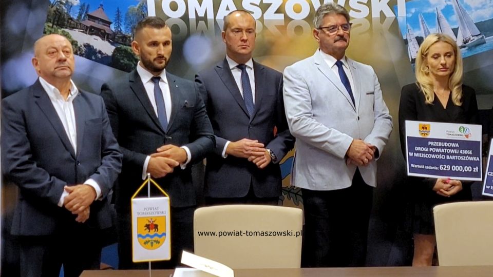 Na zdjęciu: od prawej: Katarzyna Kmita - właściciel Przedsiębiorstwa Handlowo–Usługowego KAMI, Leszek Ogórek – Wicestarosta Powiatu Tomaszowskiego, Michał Czechowicz – członek Zarządu Powiatu Tomaszowskiego, Grzegorz Glimasiński – przewodniczący Komisji Bezpieczeństwa Publicznego i Transportu, Leon Karwat – przewodniczący Komisji Edukacji, Kultury i Sportu, podczas konferencji prasowej, na której podpisane zostały umowy z wykonawcą, Firmą KAMI, na realizację zadań: Przebudowa układu komunikacyjnego w celu poprawy bezpieczeństwa w ruchu drogi powiatowej nr 4306E w miejscowości Bartoszówka  na odcinku 450 m i zadania: Przebudowa układu komunikacyjnego w celu poprawy bezpieczeństwa w ruchu drogi powiatowej nr 4306E Czerniewice – Mała Wola - Brzozów  na odcinku 990 m.