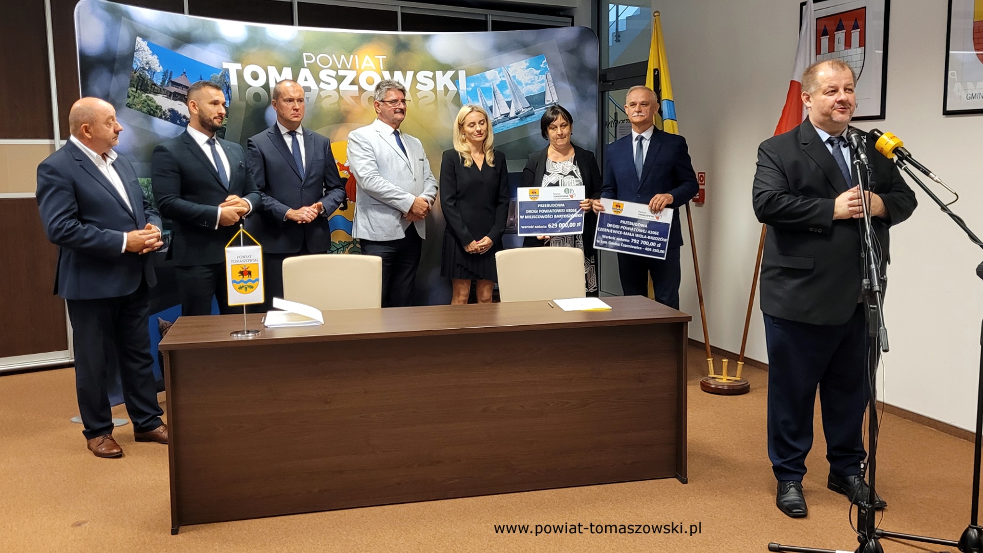 Na zdjęciu: od prawej: Mariusz Węgrzynowski – Starosta Powiatu Tomaszowskiego, Włodzimierz Justyna – przewodniczący Komisji Rewizyjnej, Katarzyna Kmita - właściciel Przedsiębiorstwa Handlowo–Usługowego KAMI, Elżbieta Rudzka – dyrektor Zarządu Dróg Powiatowych, Leszek Ogórek – Wicestarosta Powiatu Tomaszowskiego, Michał Czechowicz – członek Zarządu Powiatu Tomaszowskiego, Grzegorz Glimasiński – przewodniczący Komisji Bezpieczeństwa Publicznego i Transportu, Leon Karwat – przewodniczący Komisji Edukacji, Kultury i Sportu, podczas konferencji prasowej, na której podpisane zostały umowy z wykonawcą, Firmą KAMI, na realizację zadań: Przebudowa układu komunikacyjnego w celu poprawy bezpieczeństwa w ruchu drogi powiatowej nr 4306E w miejscowości Bartoszówka  na odcinku 450 m i zadania: Przebudowa układu komunikacyjnego w celu poprawy bezpieczeństwa w ruchu drogi powiatowej nr 4306E Czerniewice – Mała Wola - Brzozów  na odcinku 990 m.
