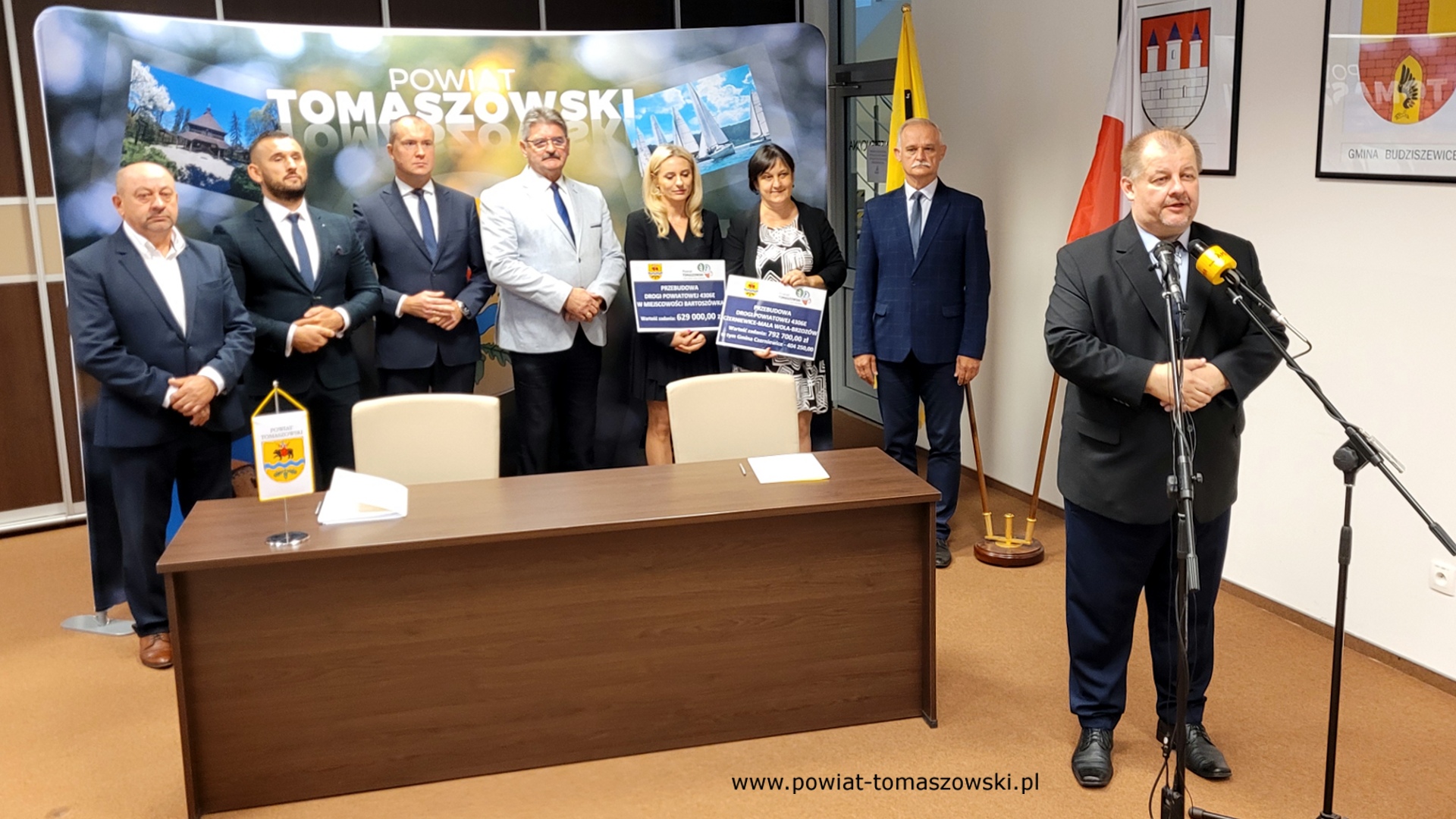 Na zdjęciu: od prawej: Mariusz Węgrzynowski – Starosta Powiatu Tomaszowskiego, Włodzimierz Justyna – przewodniczący Komisji Rewizyjnej, Katarzyna Kmita - właściciel Przedsiębiorstwa Handlowo–Usługowego KAMI, Elżbieta Rudzka – dyrektor Zarządu Dróg Powiatowych, Leszek Ogórek – Wicestarosta Powiatu Tomaszowskiego, Michał Czechowicz – członek Zarządu Powiatu Tomaszowskiego, Grzegorz Glimasiński – przewodniczący Komisji Bezpieczeństwa Publicznego i Transportu, Leon Karwat – przewodniczący Komisji Edukacji, Kultury i Sportu, podczas konferencji prasowej, na której podpisane zostały umowy z wykonawcą, Firmą KAMI, na realizację zadań: Przebudowa układu komunikacyjnego w celu poprawy bezpieczeństwa w ruchu drogi powiatowej nr 4306E w miejscowości Bartoszówka  na odcinku 450 m i zadania: Przebudowa układu komunikacyjnego w celu poprawy bezpieczeństwa w ruchu drogi powiatowej nr 4306E Czerniewice – Mała Wola - Brzozów  na odcinku 990 m.