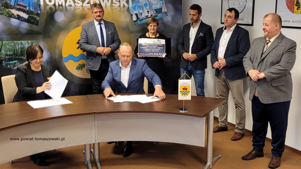Na zdjęciu: od prawej: Mariusz Węgrzynowski – Starosta Powiatu Tomaszowskiego, Dariusz Kowalczyk – radny Rady Powiatu Tomaszowskiego, Marek Kubiak – członek Zarządu Powiatu Tomaszowskiego, Elżbieta Łojszczyk - członek Zarządu Powiatu Tomaszowskiego, Leszek Ogórek – Wicestarosta Powiatu Tomaszowskiego, siedzą: Elżbieta Rudzka – dyrektor Zarządu Dróg Powiatowych i Ryszard Skoneczny – właściciel FH Agro-Trans z Czerniewic, wykonawca prac, podczas konferencji prasowej, na której podpisana została umowa na realizację zadania pod nazwą: Modernizacja drogi powiatowej 4306E na odcinku Czerniewice – Mała Wola - Brzozów w obrębach miejscowości Dzielnica, Mała Wola, na odcinku 1450 m (500 m w miejscowości Mała Wola, 950 m miejscowości Dzielnica), która odbyła się w środę, 3 listopada 2021 roku, w sali konferencyjnej w Starostwie Powiatowym w Tomaszowie Mazowieckim