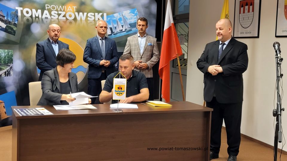 Na zdjęciu: od prawej stoją: Mariusz Węgrzynowski – Starosta Powiatu Tomaszowskiego, Marek Kubiak – członek Zarządu Powiatu Tomaszowskiego, Włodzimierz Justyna – przewodniczący Komisji Rewizyjnej, Leon Karwat – przewodniczący Komisji Edukacji, Kultury i Sportu Rady Powiatu Tomaszowskiego, siedzą: Elżbieta Rudzka – dyrektor Zarządu Dróg Powiatowych i Sebastian Śliwiński – właściciel Firmy P.P.H.U. Sebastian Śliwiński, podczas podpisania umowy na realizację zadania pod nazwą: „Budowa utwardzonego pobocza w ciągu drogi powiatowej Nr 4310E  ul. Zielona w Rzeczycy”
