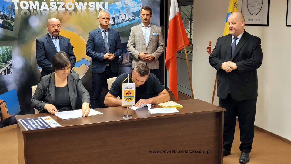Na zdjęciu: od prawej stoją: Mariusz Węgrzynowski – Starosta Powiatu Tomaszowskiego, Marek Kubiak – członek Zarządu Powiatu Tomaszowskiego, Włodzimierz Justyna – przewodniczący Komisji Rewizyjnej, Leon Karwat – przewodniczący Komisji Edukacji, Kultury i Sportu Rady Powiatu Tomaszowskiego, siedzą: Elżbieta Rudzka – dyrektor Zarządu Dróg Powiatowych i Sebastian Śliwiński – właściciel Firmy P.P.H.U. Sebastian Śliwiński, podczas podpisania umowy na realizację zadania pod nazwą: „Budowa utwardzonego pobocza w ciągu drogi powiatowej Nr 4310E  ul. Zielona w Rzeczycy”