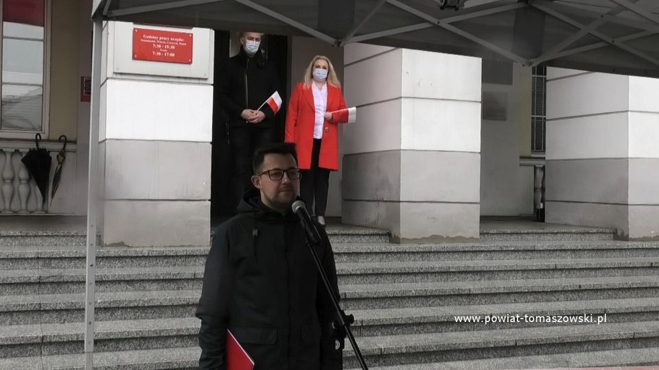 Na zdjęciu: Bartłomiej Składowski, z tyłu Izabela Śliwińska – Wiceprezydent Tomaszowa Mazowieckiego i Tomasz Migała – zastępca dyrektora Wydziału Edukacji, Kultury i Sportu Urzędu Miasta, podczas obchodów Dnia Flagi Rzeczypospolitej Polskiej w Tomaszowie Mazowieckim, 2 maja 2021 roku