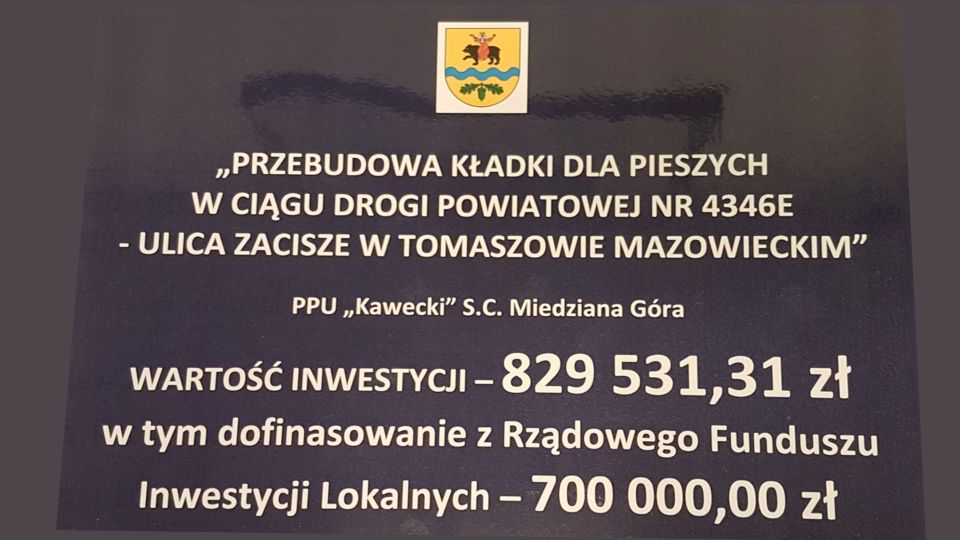 Na zdjęciu: baner promujący zadanie „Przebudowa kładki dla pieszych w ciągu drogi powiatowej nr 4346E – ulica Zacisze w Tomaszowie Mazowieckim”,, które zostanie zrealizowane przez Przedsiębiorstwo Produkcyjno-Usługowe „Kawecki” s.c., za kwotę 829 531,31 zł, w tym dofinansowanie z Rządowego Funduszu Inwestycji Lokalnych 700 tysięcy złotych