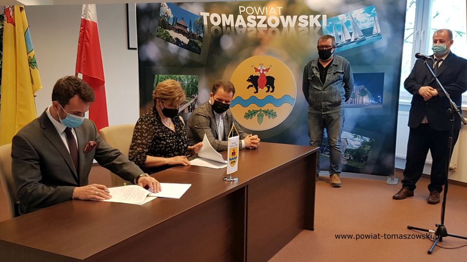 Na zdjęciu: stoją od prawej: Mariusz Węgrzynowski – Starosta Powiatu Tomaszowskiego, i Krzysztof Tarkowski – podinspektor Wydziału Inwestycji i Pozyskiwania Środków, za biurkiem: Paweł Siminiak – właściciel Przedsiębiorstwa Budowlanego Pagma-Bud, Elżbieta Łojszczyk - członek Zarządu Powiatu Tomaszowskiego, Marek Kubiak – członek Zarządu Powiatu Tomaszowskiego,  podczas podpisania umowy z wykonawcą zadania pn. „Adaptacja budynku położonego na terenie Specjalnego Ośrodka Szkolno-Wychowawczego w Tomaszowie Mazowieckim z przeznaczeniem na rehabilitację zawodową i społeczną osób niepełnosprawnych”