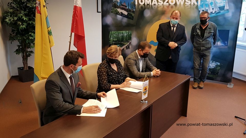 Na zdjęciu: stoją od prawej: Krzysztof Tarkowski – podinspektor Wydziału Inwestycji i Pozyskiwania Środków, Mariusz Węgrzynowski – Starosta Powiatu Tomaszowskiego, za biurkiem: Paweł Siminiak – właściciel Przedsiębiorstwa Budowlanego Pagma-Bud, Elżbieta Łojszczyk - członek Zarządu Powiatu Tomaszowskiego, Marek Kubiak – członek Zarządu Powiatu Tomaszowskiego,  podczas podpisania umowy z wykonawcą zadania pn. „Adaptacja budynku położonego na terenie Specjalnego Ośrodka Szkolno-Wychowawczego w Tomaszowie Mazowieckim z przeznaczeniem na rehabilitację zawodową i społeczną osób niepełnosprawnych”
